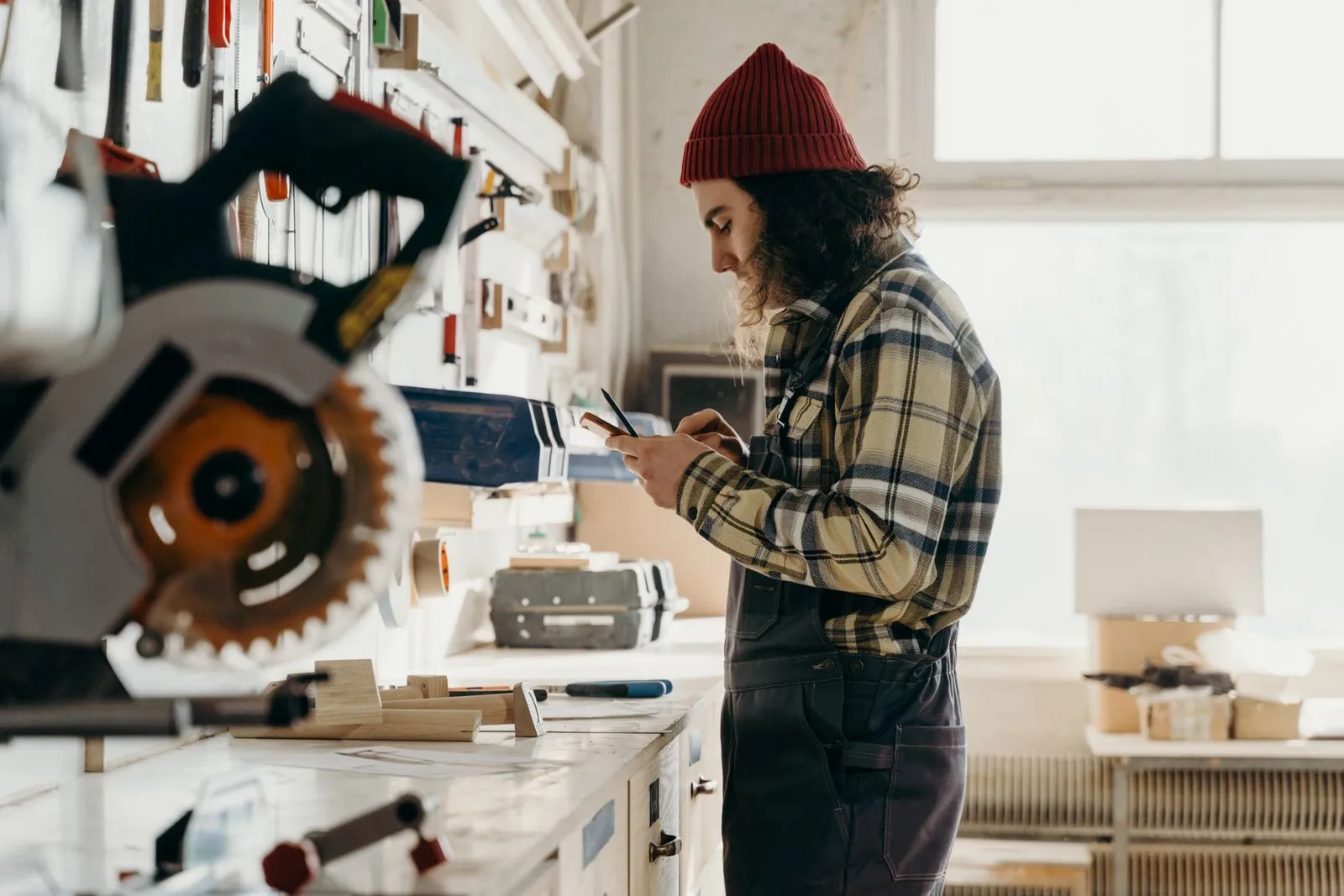 A craftsman in his workshop, checking a message on his phone