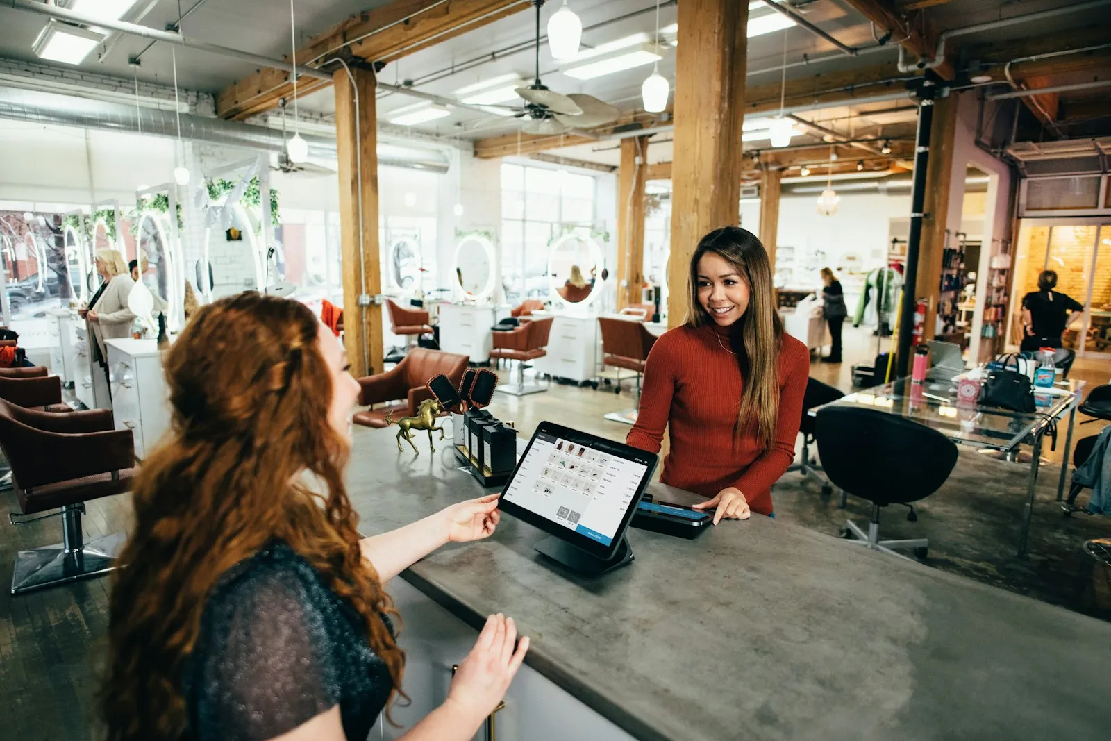 A salon receptionist smiling at a customer across the front desk